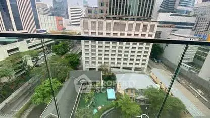 Stunning cityscape view from a high-rise balcony overlooking urban skyline and lush greenery.