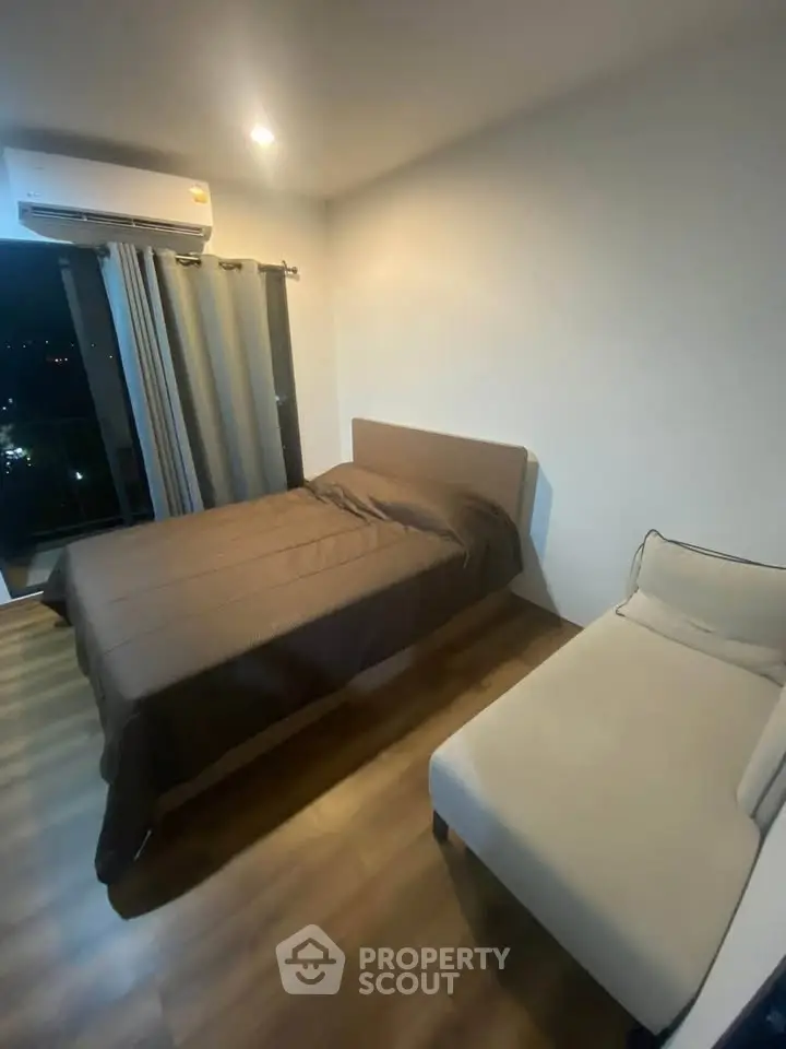 Cozy bedroom with modern furnishings and city view, perfect for urban living.