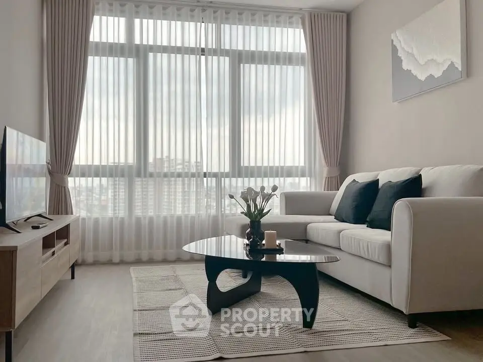 Modern living room with large windows, stylish furniture, and elegant decor in a high-rise apartment.