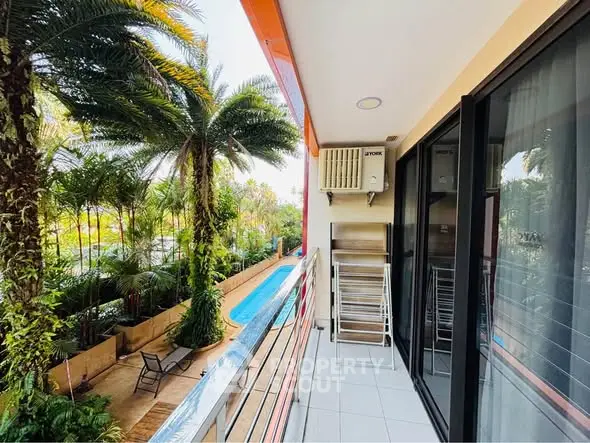 Charming balcony with pool view and lush greenery, perfect for relaxation and outdoor enjoyment.