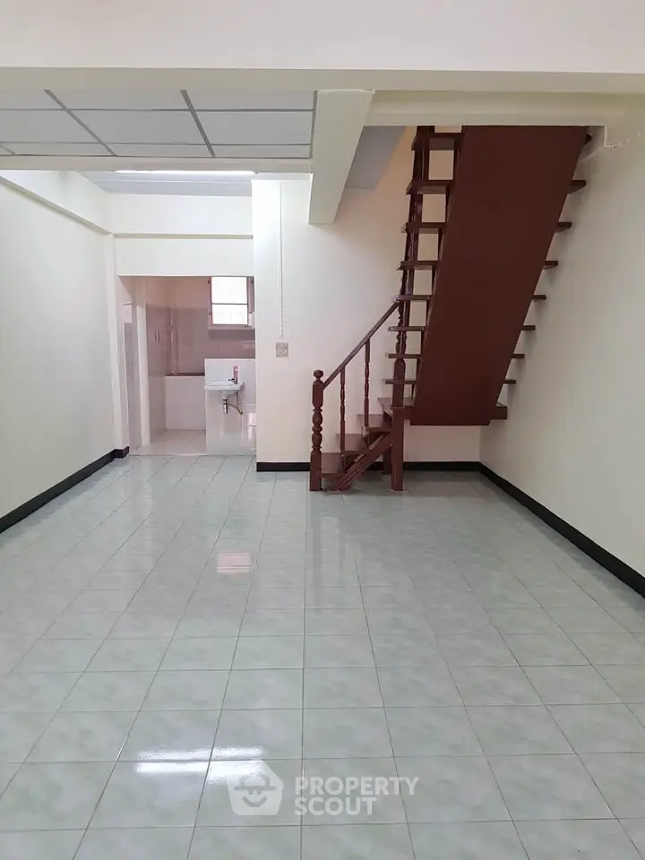 Spacious interior with tiled floors and wooden staircase, ideal for modern living.