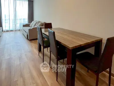 Spacious living room with wooden flooring and modern dining set, perfect for entertaining guests.
