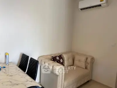 Cozy living room with elegant sofa and dining area, featuring modern air conditioning.