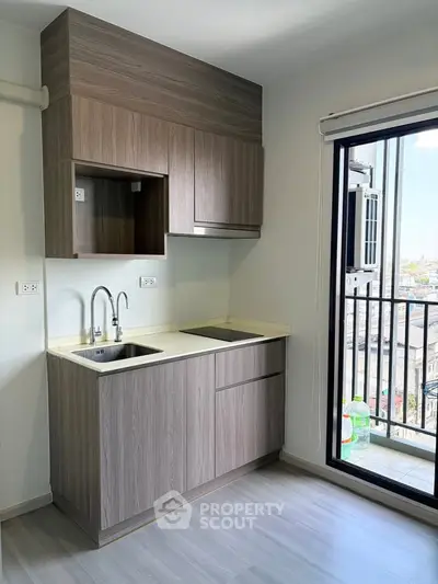 Modern kitchen with sleek cabinetry and balcony view in urban apartment