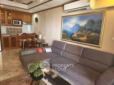 Spacious living room with modern sofa and open kitchen layout, featuring elegant decor and artwork.