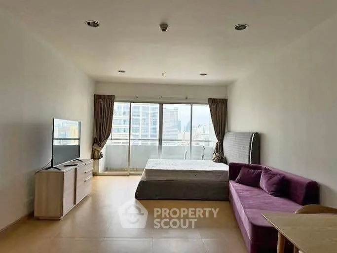 Spacious studio apartment with modern furnishings and city view balcony.