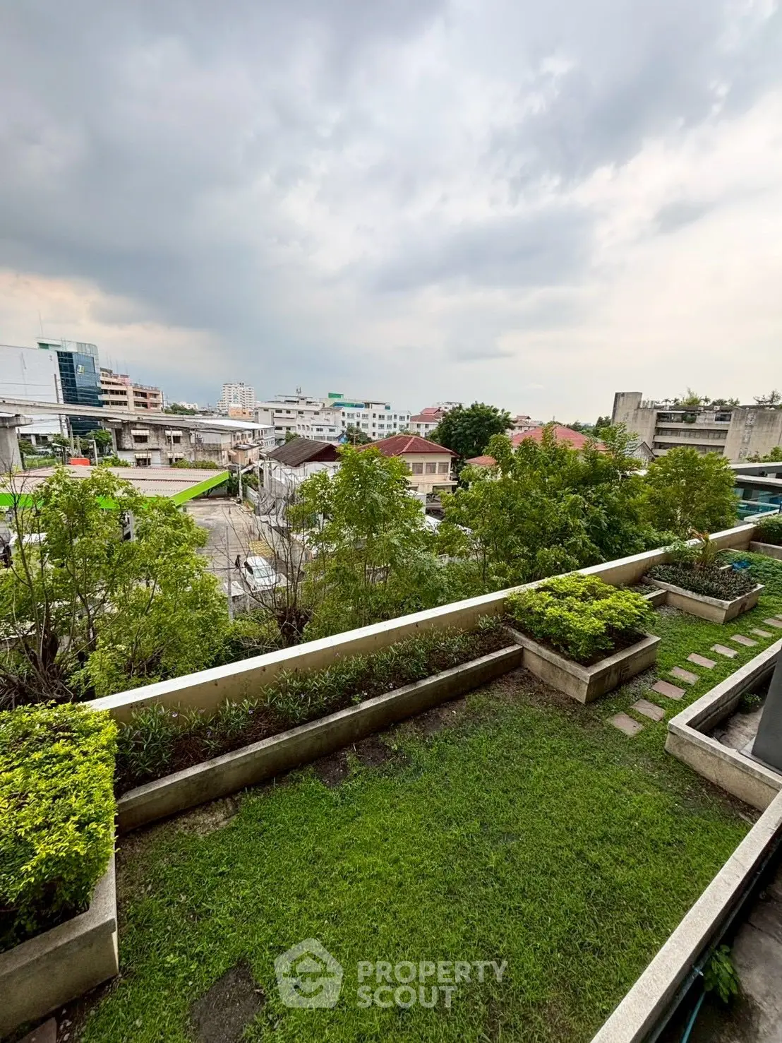 Stunning garden view from a high-rise balcony with lush greenery and cityscape backdrop.
