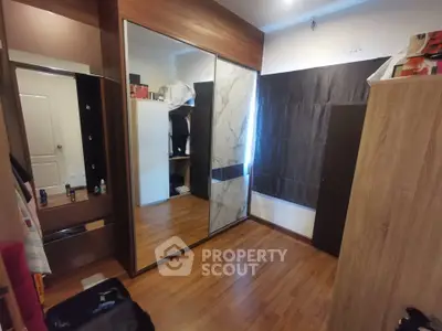 Spacious bedroom with wooden flooring and mirrored wardrobe doors