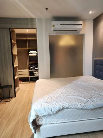 Modern bedroom with walk-in closet and air conditioning, featuring stylish wooden flooring.