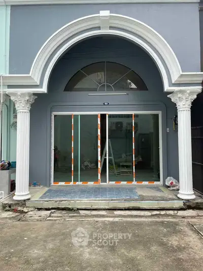 Elegant building entrance with arched doorway and classic columns, showcasing modern sliding glass doors.
