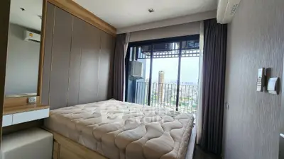 Modern bedroom with city view and balcony access, featuring elegant decor and natural light.