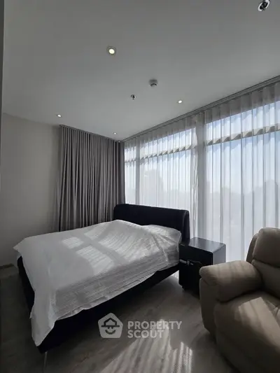 Spacious bedroom with large windows and modern furnishings in a luxury apartment.