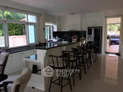 Spacious kitchen with bar seating and large windows overlooking garden