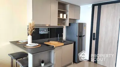 Modern compact kitchen with sleek cabinetry and stainless steel fridge