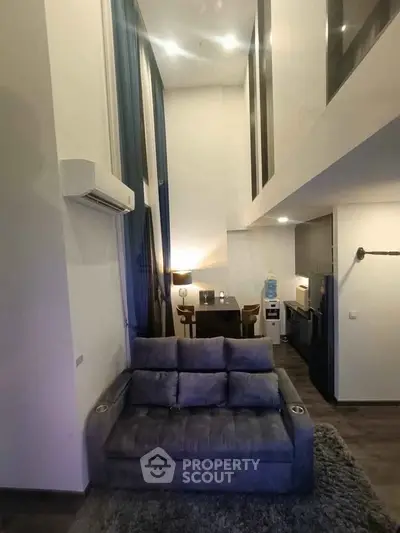 Modern loft-style living room with high ceilings and cozy furniture