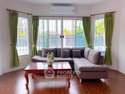 Charming living room with large windows and cozy sectional sofa, perfect for relaxation.
