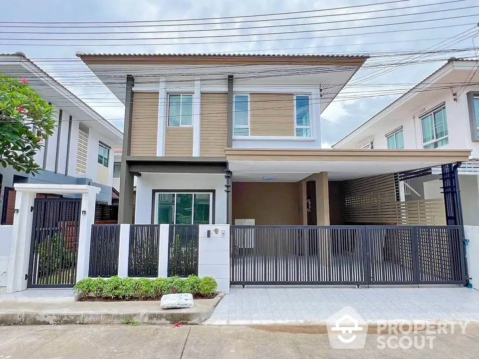 Modern two-story house with sleek design and gated entrance in a suburban neighborhood.