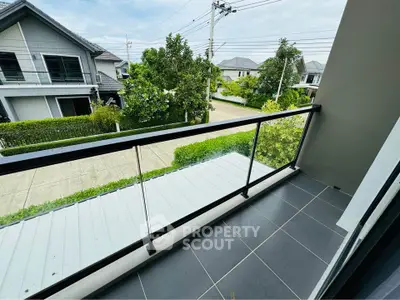 Charming balcony with modern railing overlooking suburban street and lush greenery.
