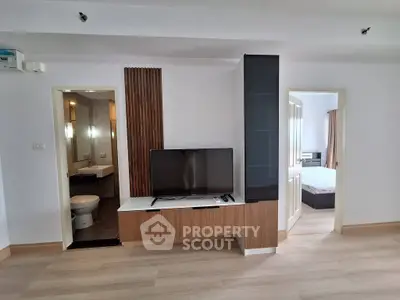 Modern apartment interior with open living area and bedroom, featuring sleek design and natural light.