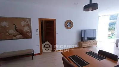 Modern living room with stylish decor and natural light, featuring a wall-mounted TV and elegant furniture.