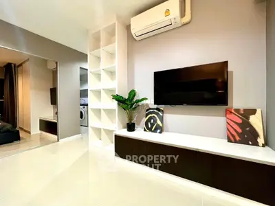 Modern living room with sleek TV setup and air conditioning, featuring stylish decor and ample storage space.