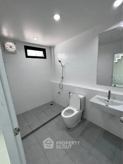 Modern bathroom with sleek design, featuring a shower, toilet, and sink in a minimalist setting.