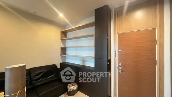 Modern apartment entrance with sleek shelving and black leather sofa