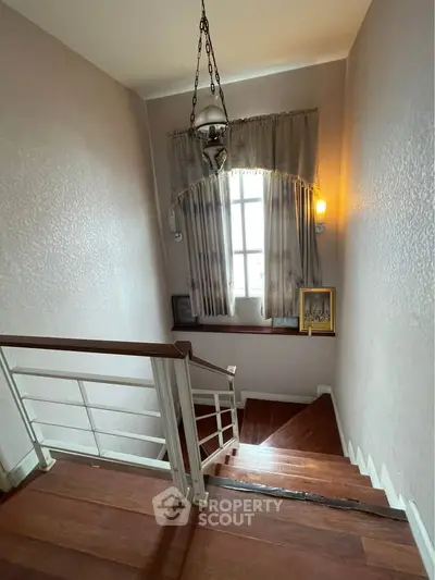 Elegant staircase with wooden steps and decorative lighting in a well-lit home interior.