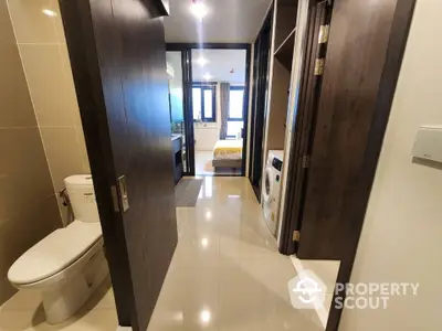 Modern apartment hallway with bathroom and laundry area, sleek design and bright lighting.