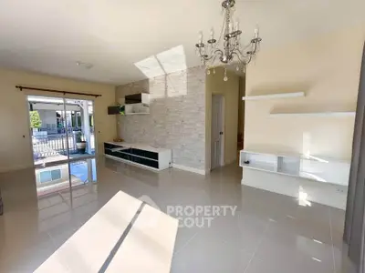 Spacious living room with elegant chandelier and modern built-in shelves, featuring large windows for natural light.