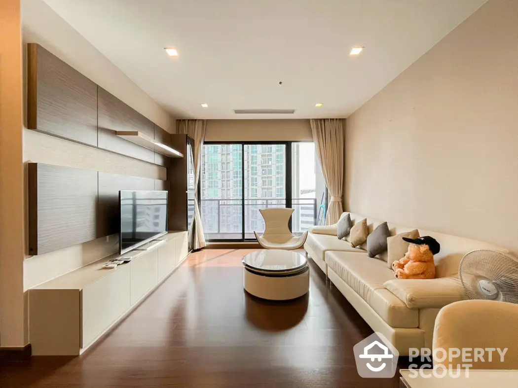 Modern living room with sleek furniture and large windows offering city views.