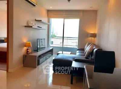 Modern living room with sleek furniture and large window offering natural light and city view.