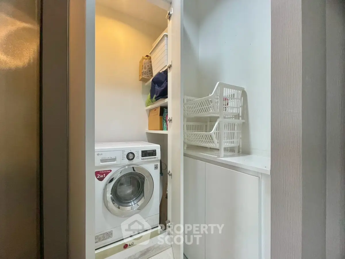 Compact laundry area with modern washing machine and storage shelves