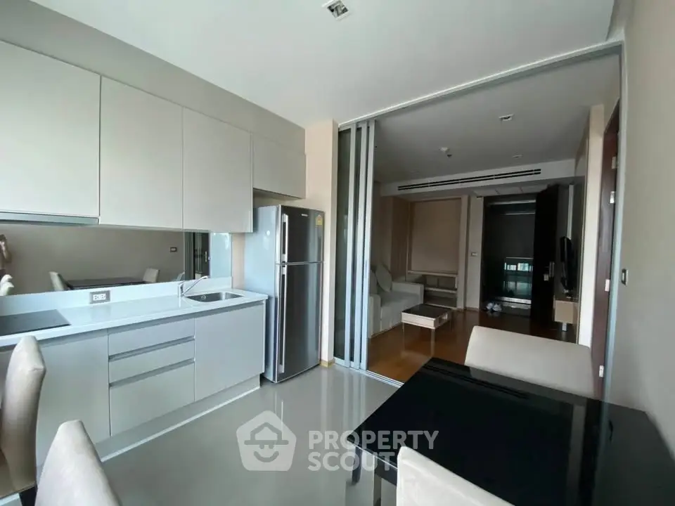 Modern open-layout kitchen with sleek cabinetry and dining area in stylish apartment.