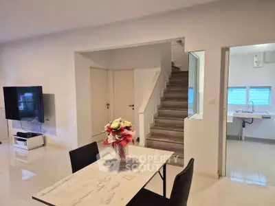 Modern open-plan living area with sleek staircase and dining table, ideal for contemporary living.