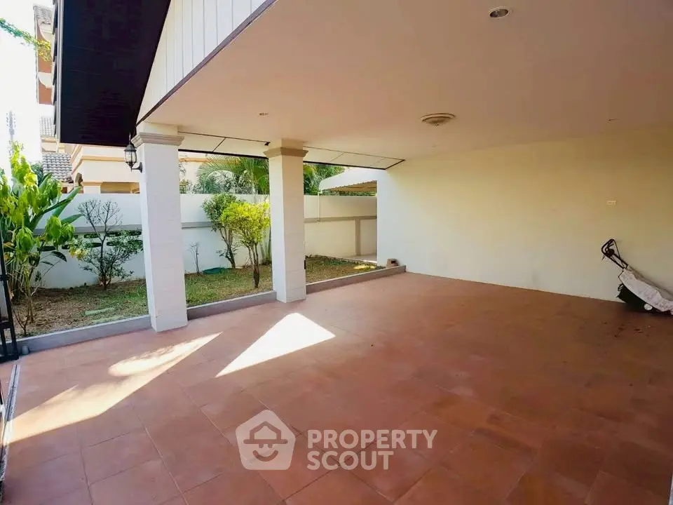 Spacious covered patio with terracotta tiles and garden view, perfect for outdoor gatherings.