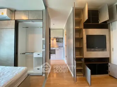 Modern apartment interior with open closet and kitchen view, featuring sleek design and wooden flooring.