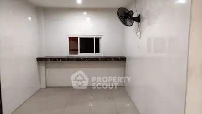 Spacious tiled room with a countertop and wall-mounted fan, ideal for versatile use.