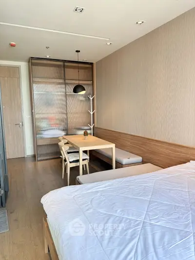 Modern bedroom with stylish decor and cozy dining area, featuring wooden accents and contemporary lighting.