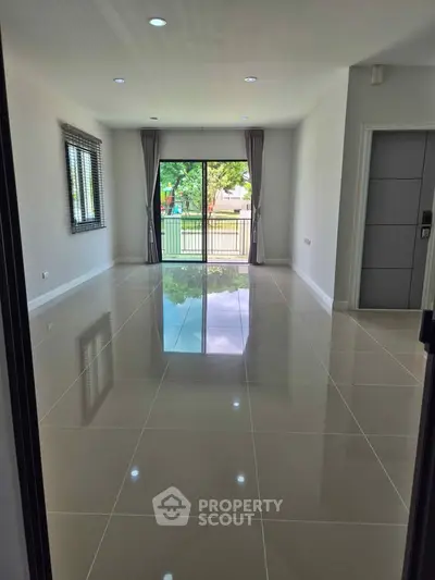 Spacious modern living room with glossy tiled floors and large windows offering natural light.