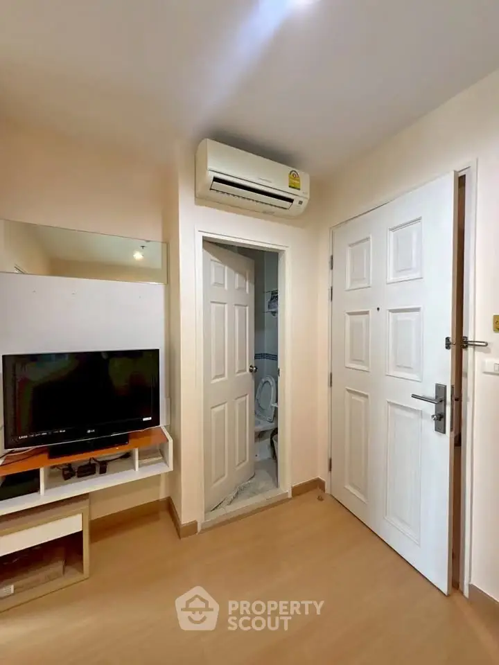 Cozy apartment entrance with TV and air conditioning, featuring a compact bathroom.
