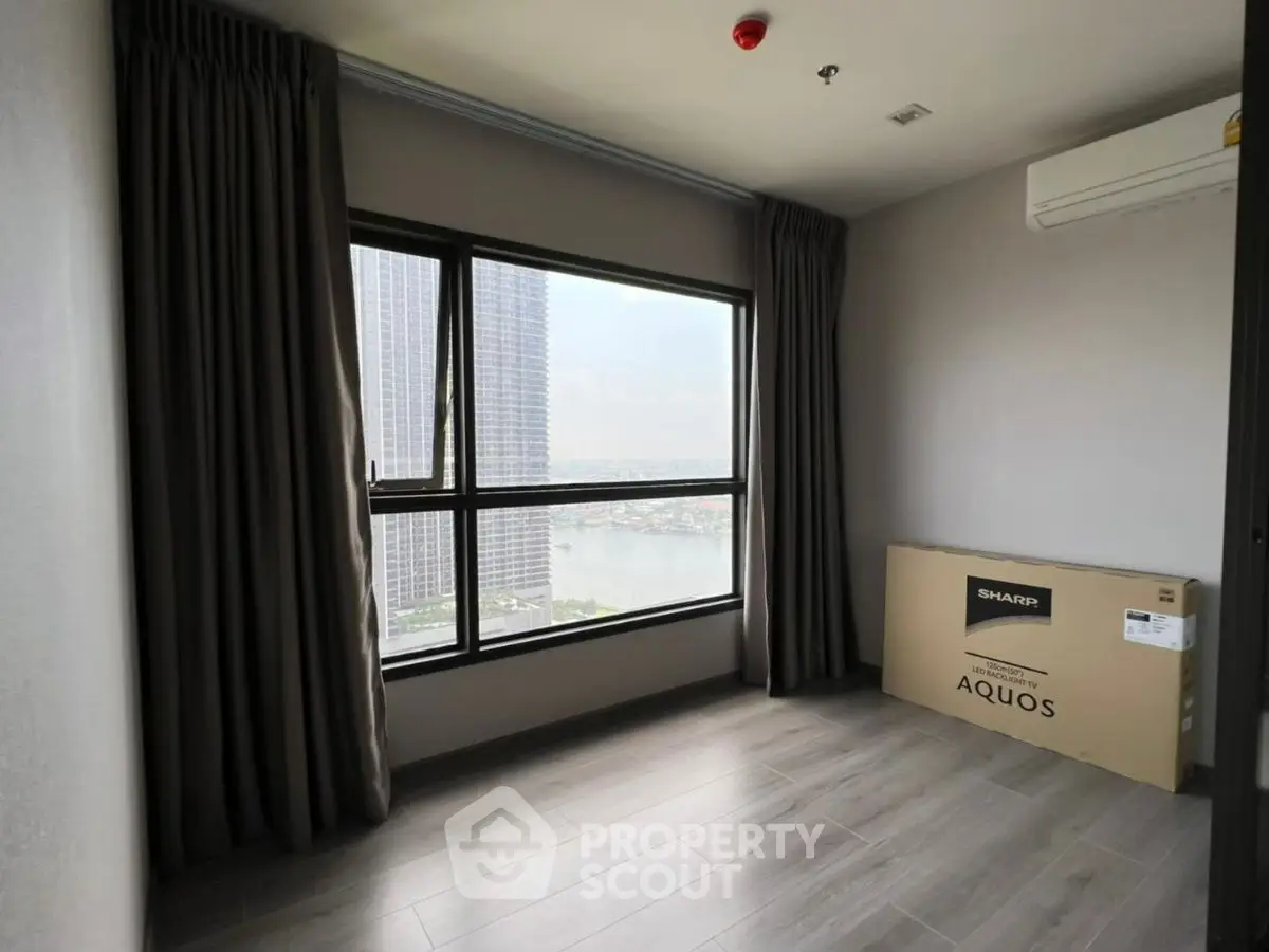 Spacious room with large window offering stunning city view, perfect for modern living.