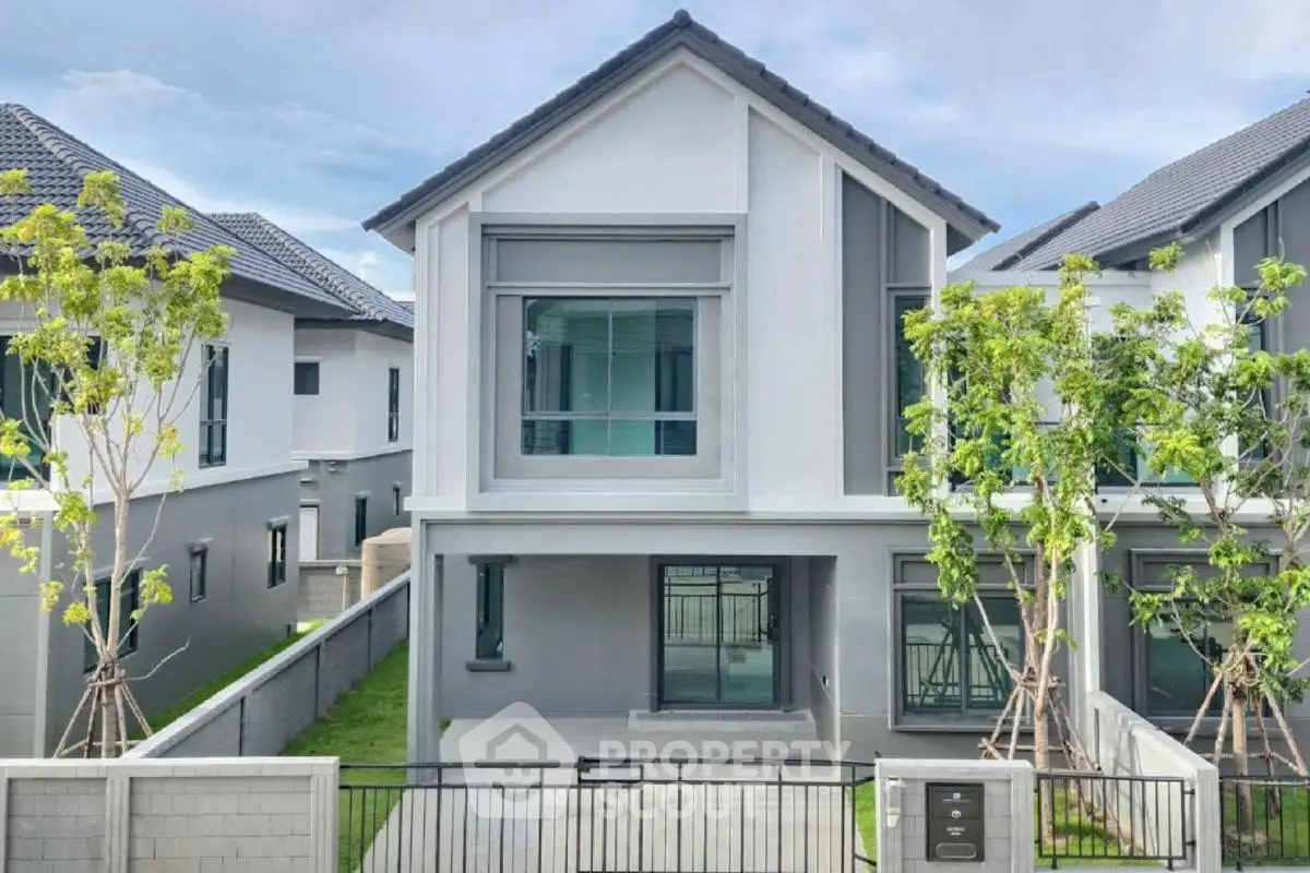 Modern two-story house with sleek design and spacious front yard in a serene neighborhood.