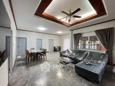 Spacious living room with modern furniture and ceiling fan, ideal for family gatherings.