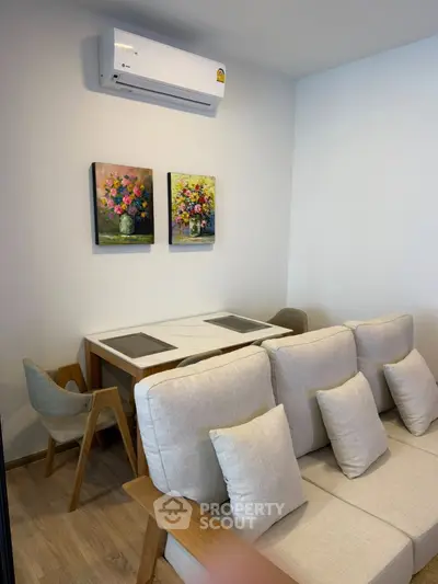 Modern living room with stylish furniture and wall art, featuring a cozy seating area and air conditioning.