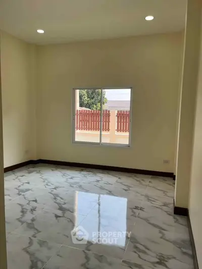 Spacious room with marble flooring and large window, perfect for natural light.