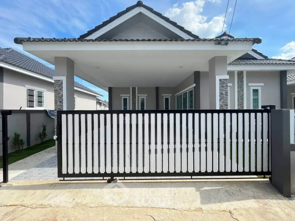 Modern single-story house with gated entrance and stylish facade under a clear blue sky.
