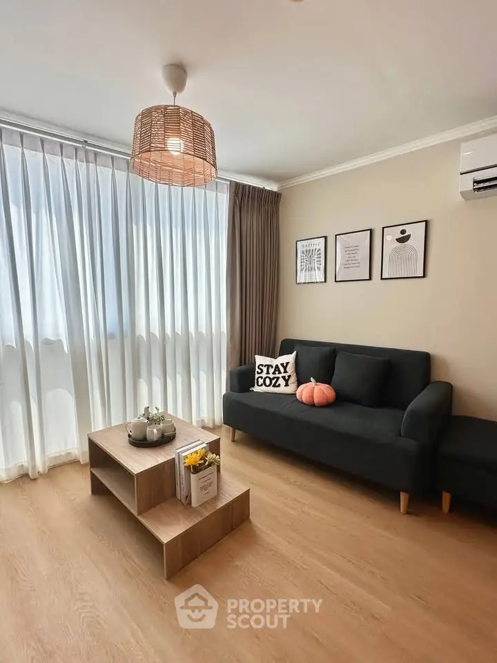 Charming living room with cozy decor, modern sofa, and natural light through sheer curtains.