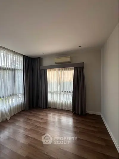 Spacious empty room with large windows and elegant curtains, perfect for customization.