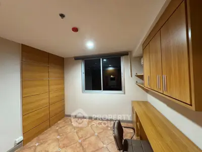 Modern study room with wooden cabinets and desk, featuring a large window for natural light.